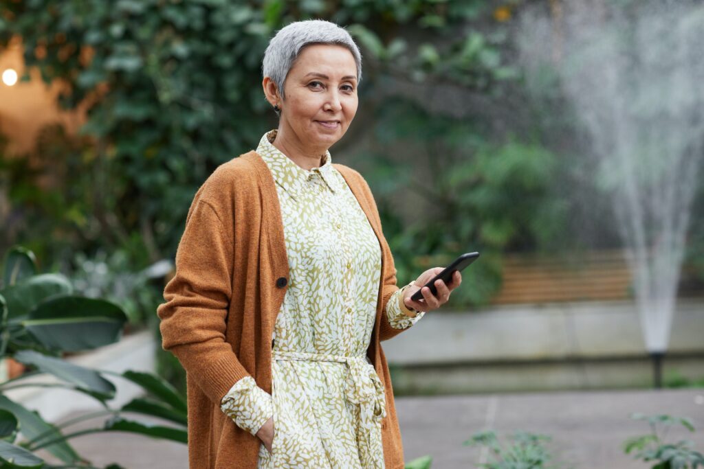 woman smiling holding her phone in one hand an other hand in her pocket