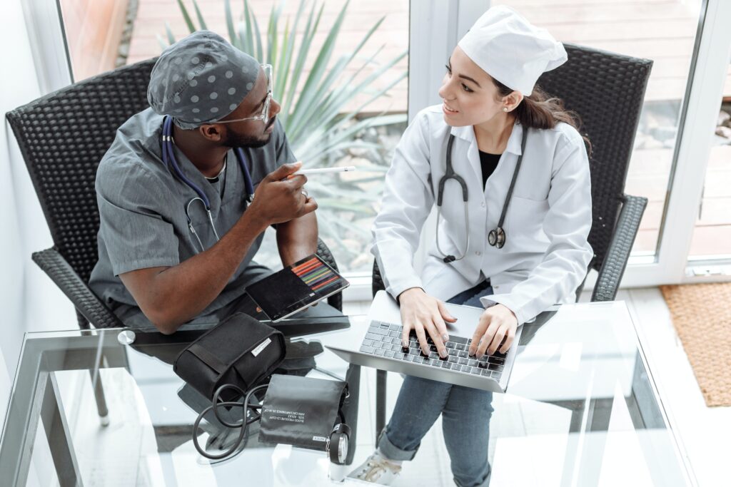 two medical personnel sitting at a desk talking